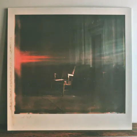 雾红相纸的旧戏院空椅 / solitary worn theater chair centered within a thick white photograph border, · Square